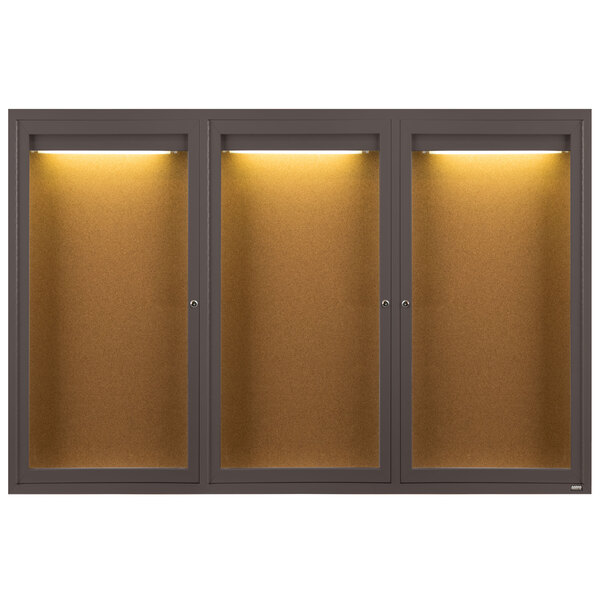 A brown Aarco bulletin board cabinet with three glass doors with lights.