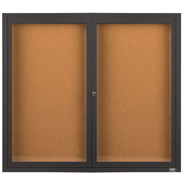 A bronze Aarco enclosed bulletin board cabinet with glass doors.