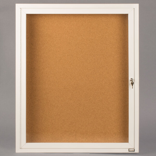 A white Aarco indoor bulletin board cabinet with a glass door and keyhole.