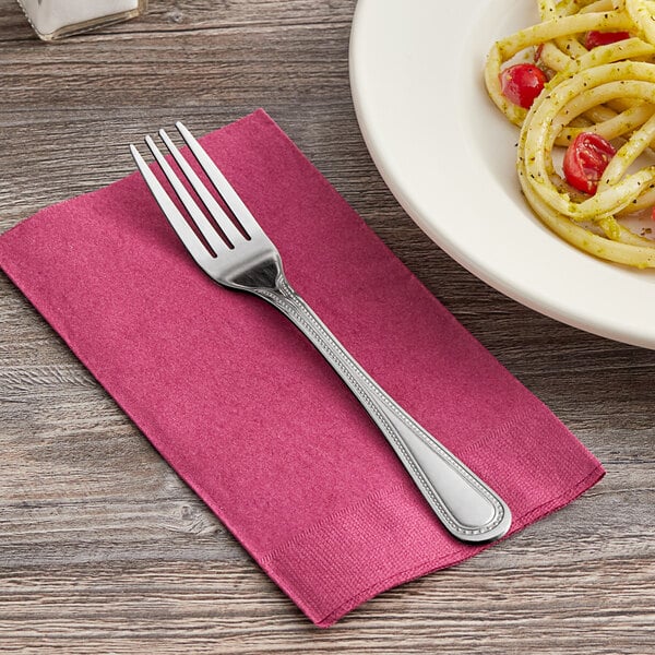 A Choice Milton stainless steel dinner fork on a plate of spaghetti with tomatoes.