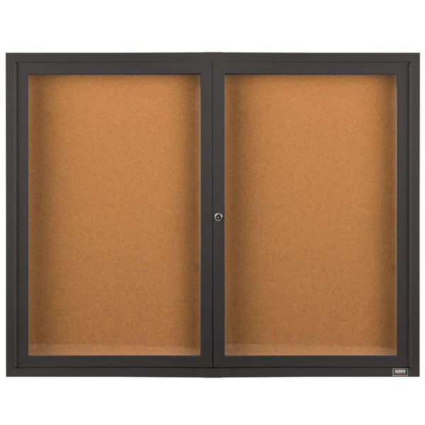 A brown rectangular Aarco bulletin board cabinet with black border and glass doors enclosing cork boards.