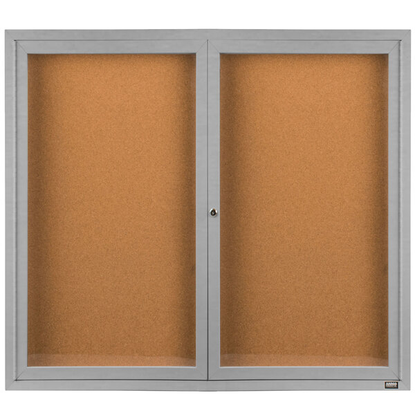 An Aarco satin anodized indoor bulletin board cabinet with two enclosed glass doors.