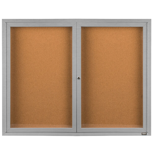 An Aarco bulletin board cabinet with two enclosed glass doors.