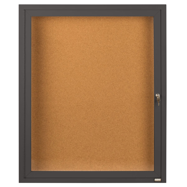 A brown cork bulletin board cabinet with a glass door and key lock.