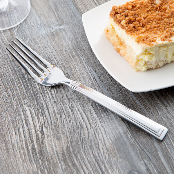 A Libbey stainless steel utility/dessert fork cutting a piece of cake on a plate.