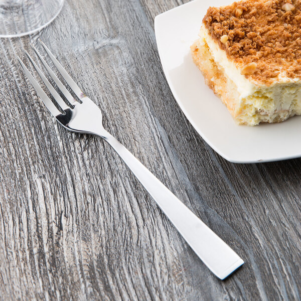 A Libbey stainless steel utility/dessert fork on a plate with a piece of cake.