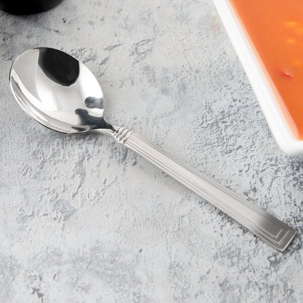 A Libbey stainless steel bouillon spoon with soup in a bowl.