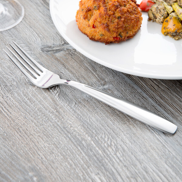 A Libbey stainless steel dinner fork on a plate of food.