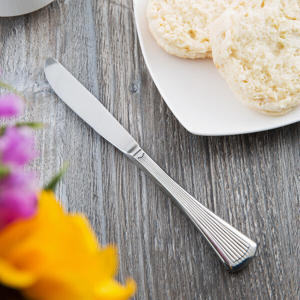 A Libbey stainless steel bread and butter knife on a plate of biscuits.