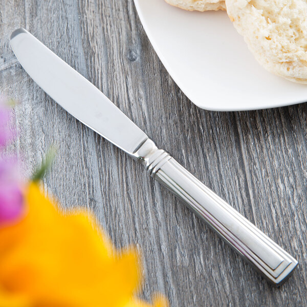 A Libbey stainless steel bread and butter knife with a plain blade on a plate with a white bread slice.