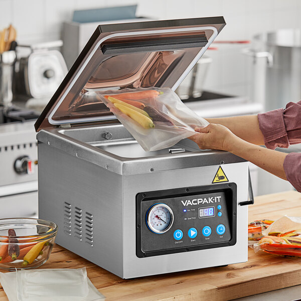 A woman using a VacPak-It chamber vacuum packaging machine to seal vegetables.