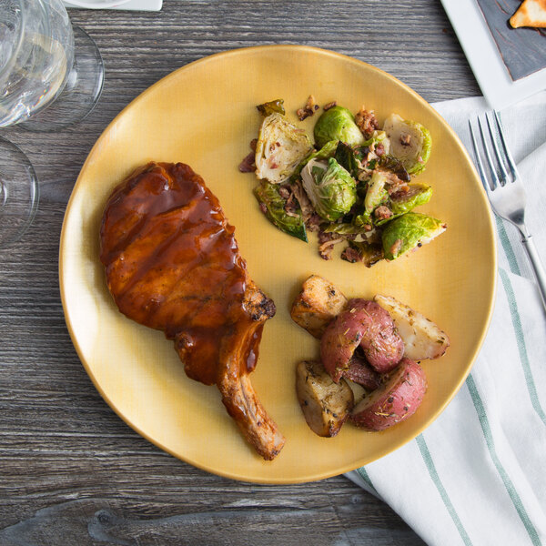 A Thunder Group gold pearl melamine plate with meat, potatoes, and brussels sprouts on a table.