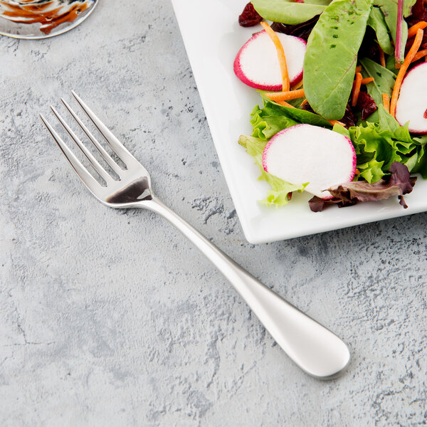 A Reserve by Libbey stainless steel salad fork next to a plate of salad.