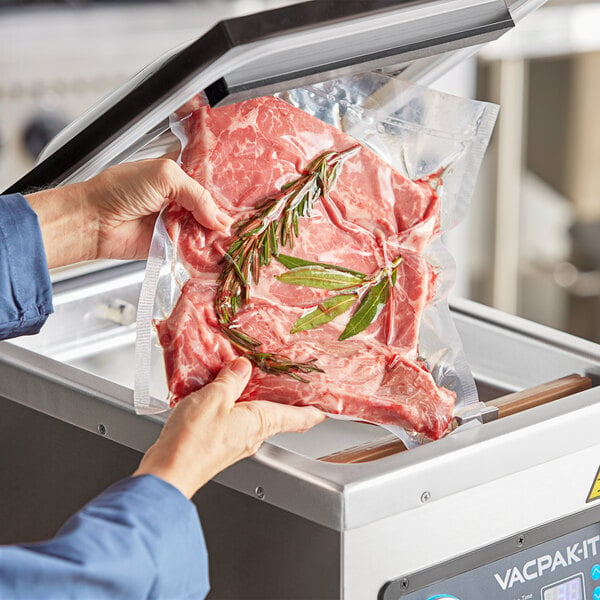 A person holding a VacPak-It vacuum packaging bag with a piece of raw meat inside.