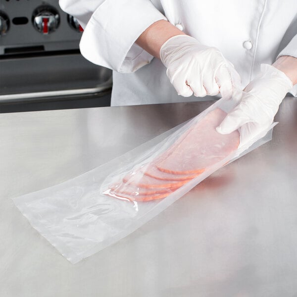 A person wearing white gloves using a VacPak-It chamber vacuum packaging pouch to pack meat.