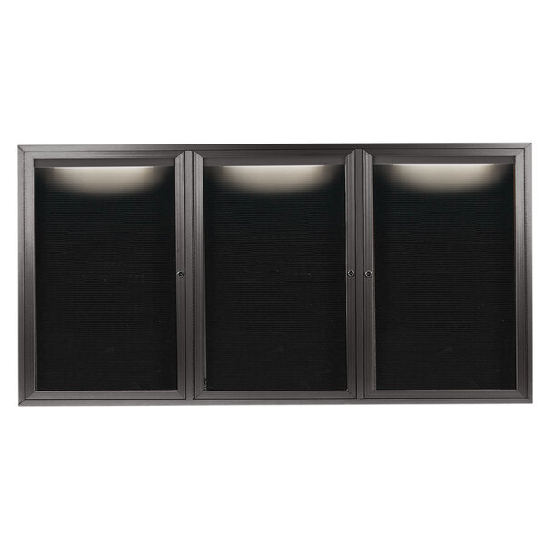 A black rectangular Aarco message center with three glass doors and a white letter board inside.