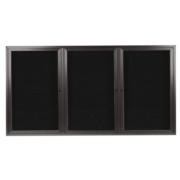 A black rectangular Aarco indoor message center with bronze aluminum frame and three black doors with glass panels.