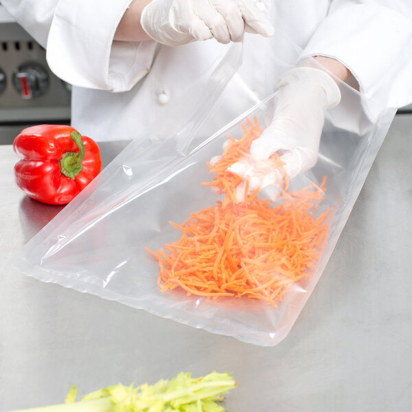 A person in gloves using a VacPak-It plastic bag to hold carrots.
