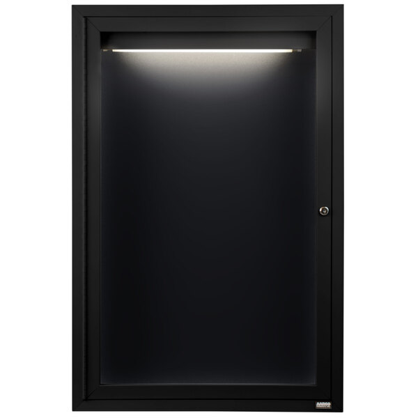 A black cabinet with a light on it and a black framed door.
