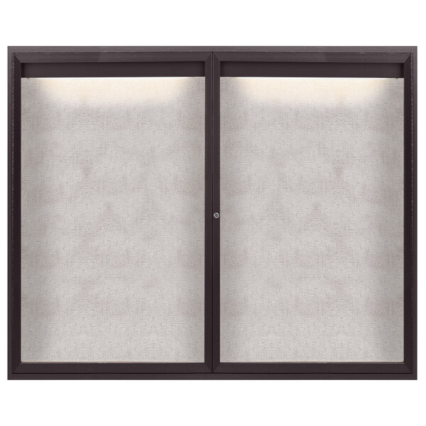 A bronze Aarco bulletin board cabinet with two glass doors with white frames.