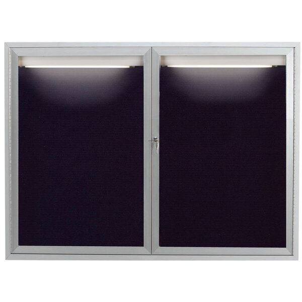A black and silver framed Aarco indoor message center with a light on a black letter board.