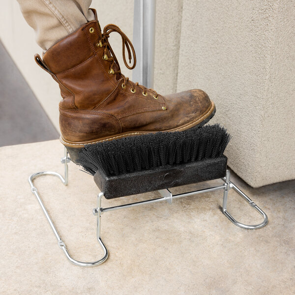 A brown boot with laces on a Carlisle shoe brush.