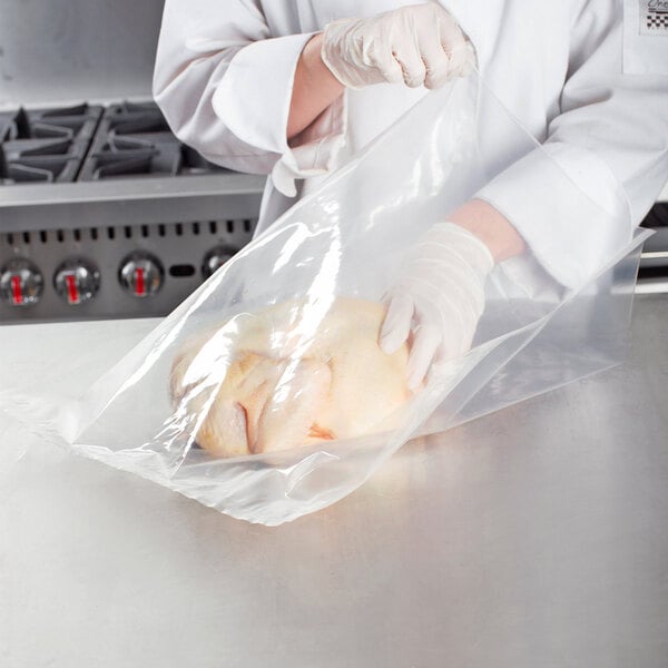 A person in a white coat and gloves using a VacPak-It plastic bag to vacuum package a chicken.
