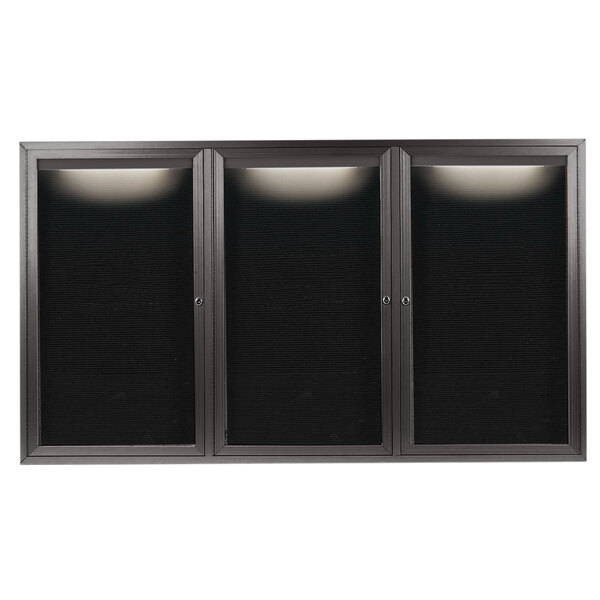 A black rectangular bronze anodized aluminum cabinet with three black glass doors and a white interior with lights.