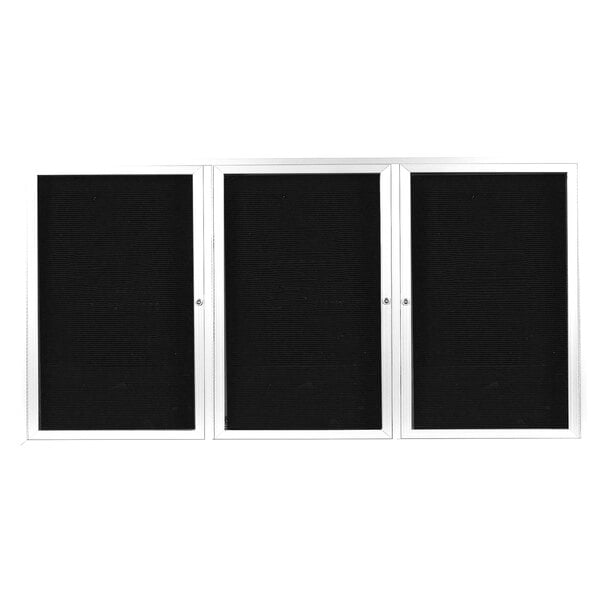 A white rectangular message center with three black doors and white frames.