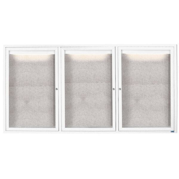 A white Aarco enclosed bulletin board cabinet with three glass doors.