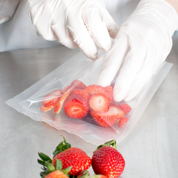 A person in gloves putting strawberries in a VacPak-It plastic bag.
