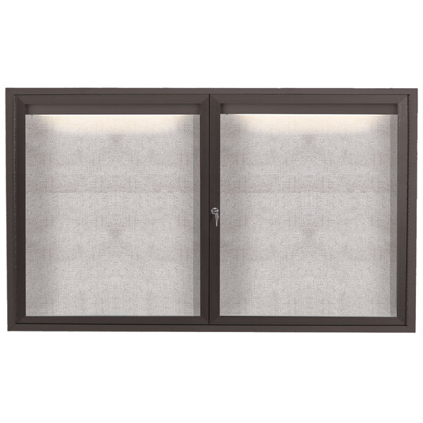 A bronze Aarco outdoor bulletin board with two glass doors and a lighted panel.