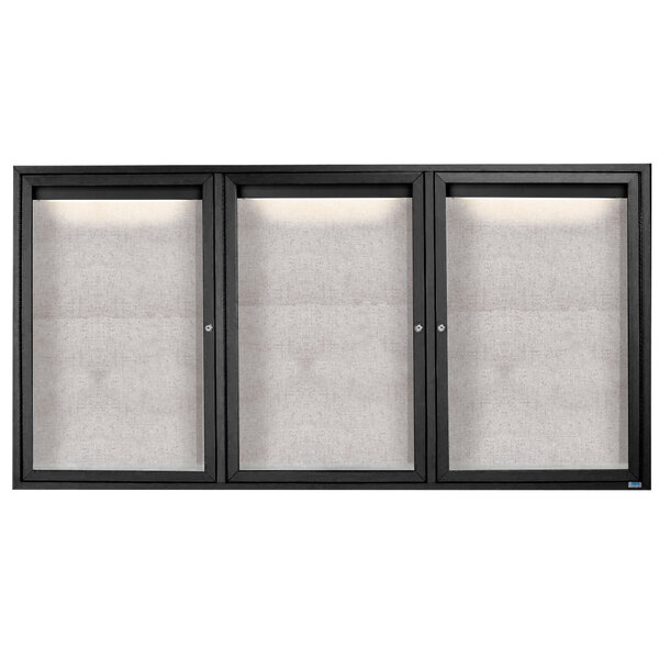 A black cabinet with three glass doors and a white rectangular board inside with a black frame.