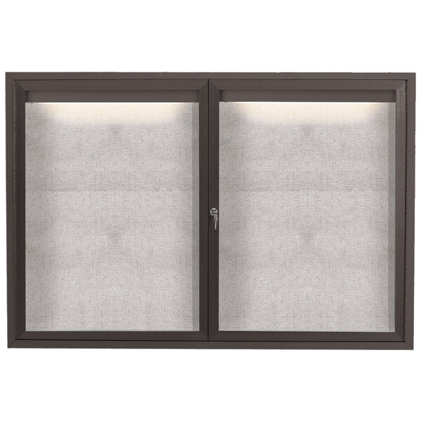 The glass doors of a bronze Aarco outdoor bulletin board.