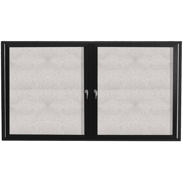 A black cabinet with white doors on a black and white framed outdoor bulletin board.