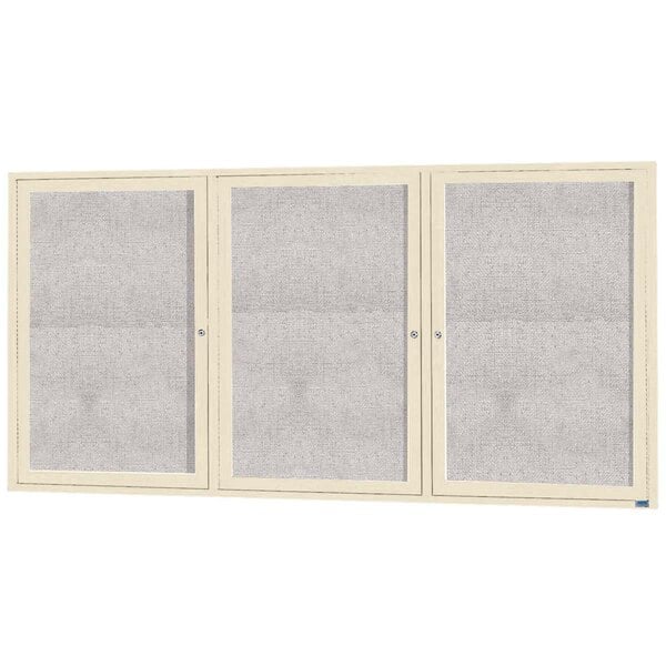 An ivory bulletin board cabinet with three glass doors.