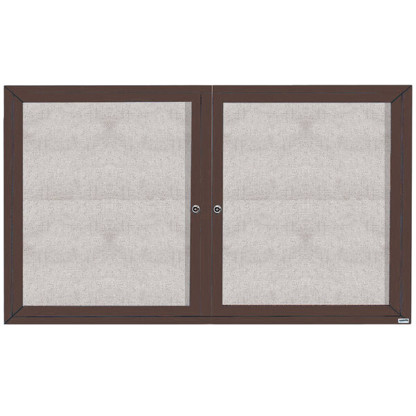 A bronze anodized Aarco outdoor bulletin board cabinet with two glass doors and a white screen.