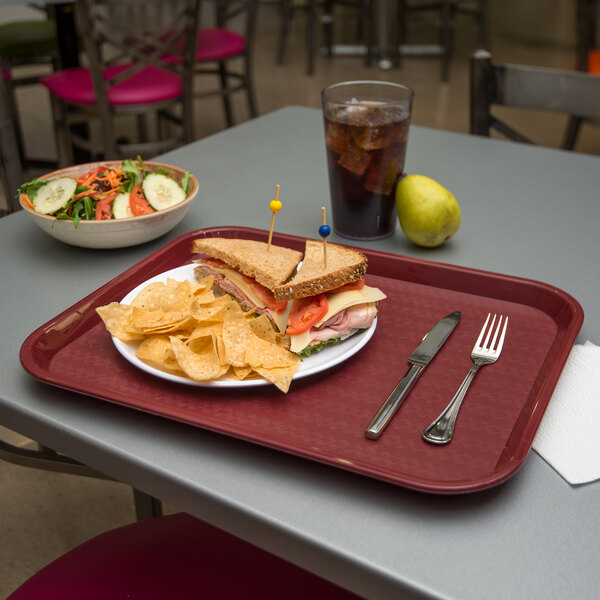 A Carlisle cafeteria tray with a sandwich, chips, and a drink on it.