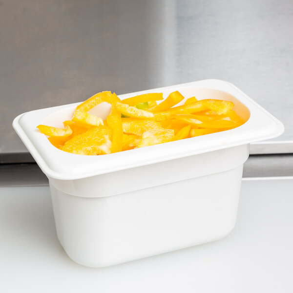 A white Cambro plastic food pan on a counter filled with orange slices.