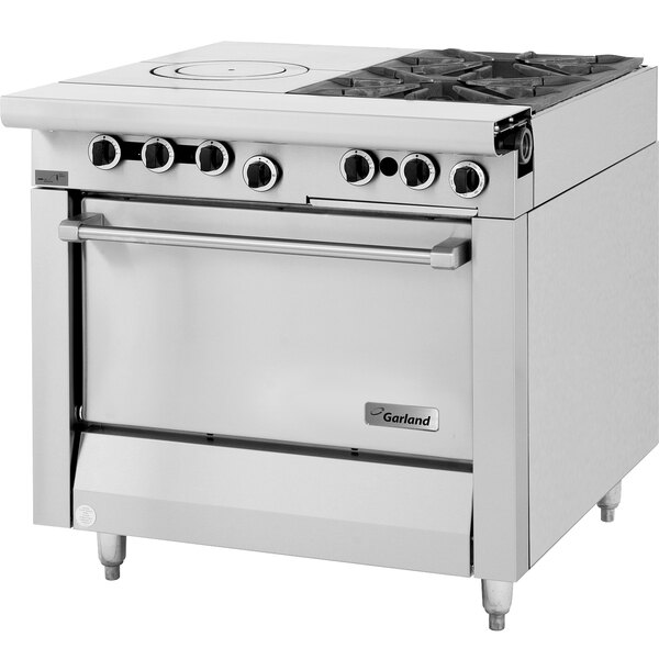 A large stainless steel Garland commercial gas range with two burners and a hot top over a standard oven.
