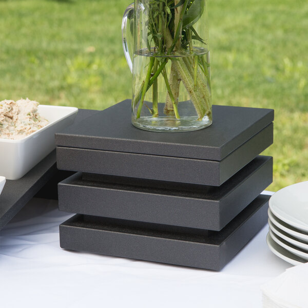 A black wooden stackable cube riser with a white bowl of food on top.