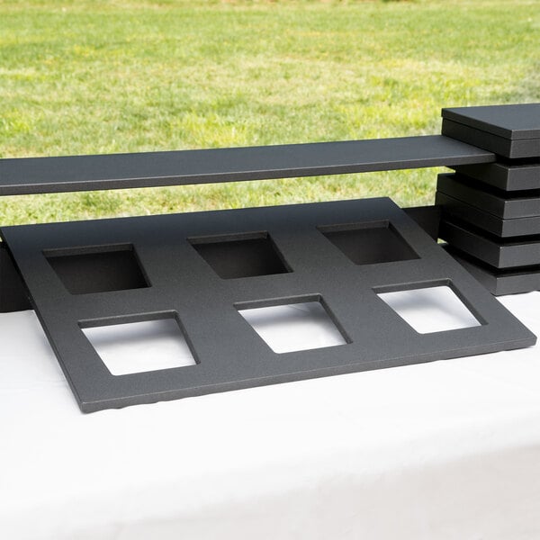 A black rectangular Vollrath wood display template with four holes on top.