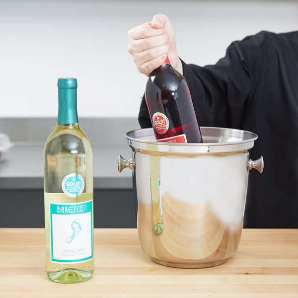 A man putting a bottle of wine into a Vollrath wine bucket.