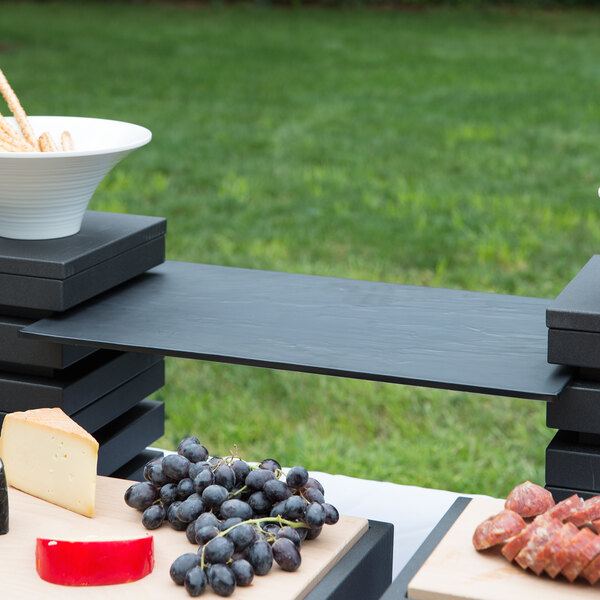 A table with food on a Vollrath slate melamine display platter.