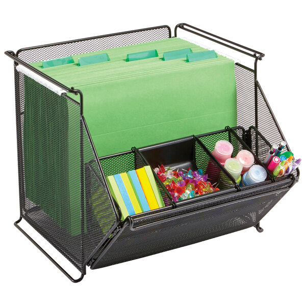 A black wire mesh Safco storage bin with green folders and stationery.