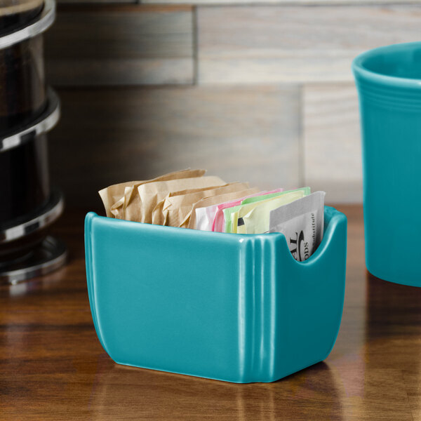 A turquoise Fiesta sugar caddy with tea bags inside.