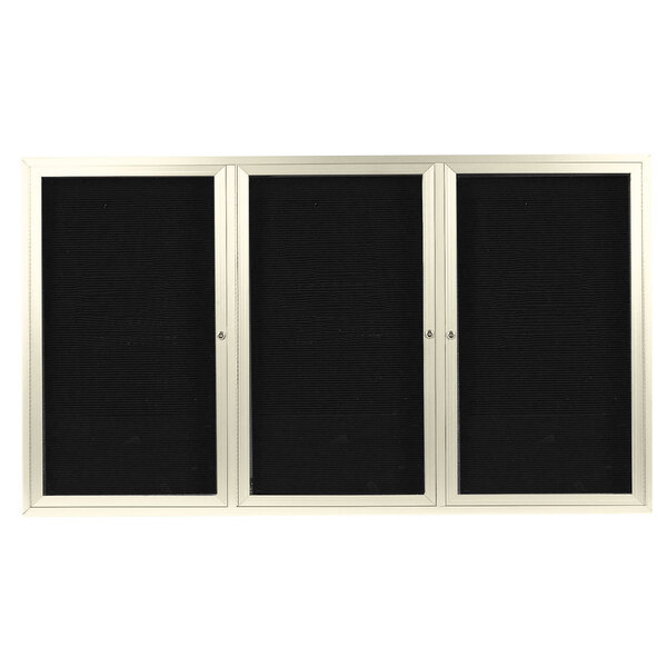 A black board with a silver frame and three black doors with white frames.