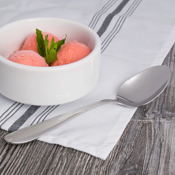 A bowl of pink ice cream with a Oneida Scroll stainless steel teaspoon.