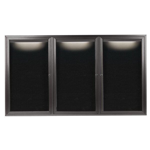 A black rectangular bronze aluminum message center with three black glass doors and a white letter board inside.