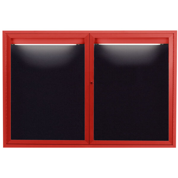 A red enclosed bulletin board with black letter board and lights on the windows.